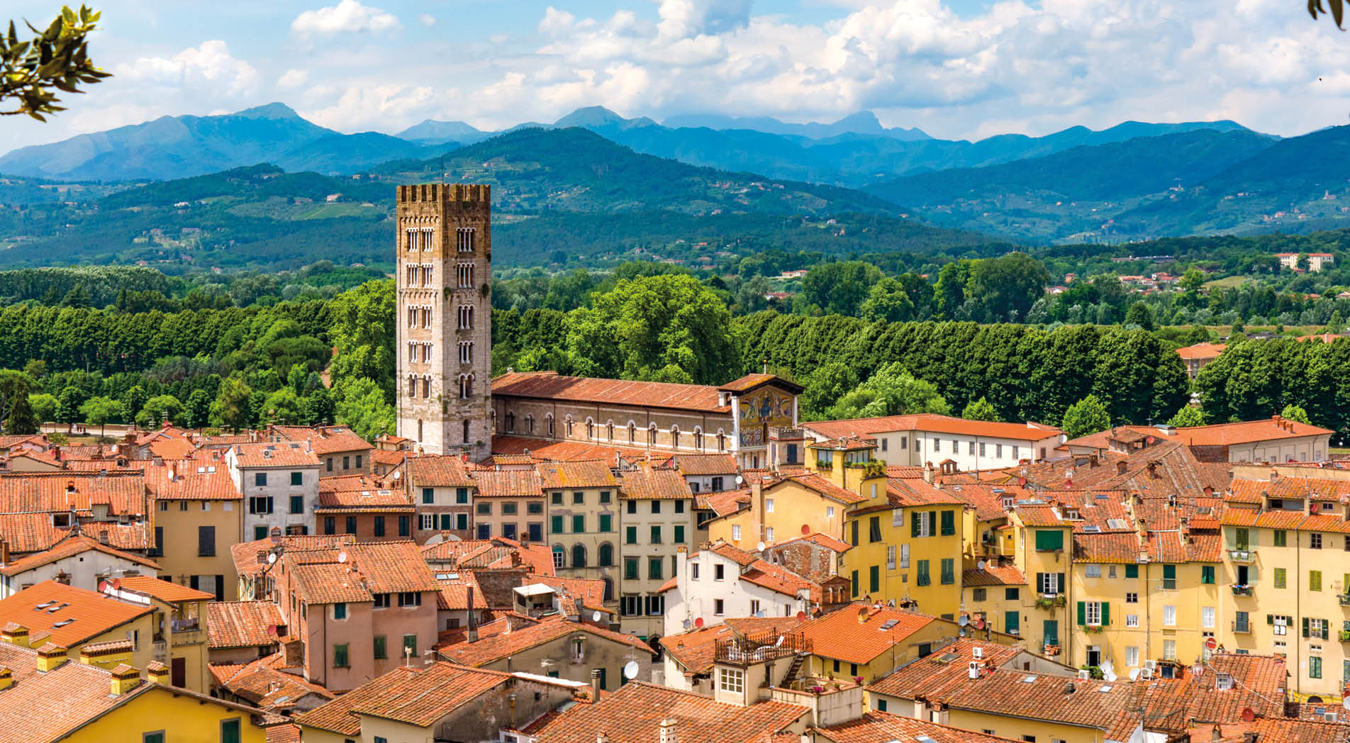 A view of the rooftops of the quaint Tuscan town of Lucca, Italy with mountain landscape in the background