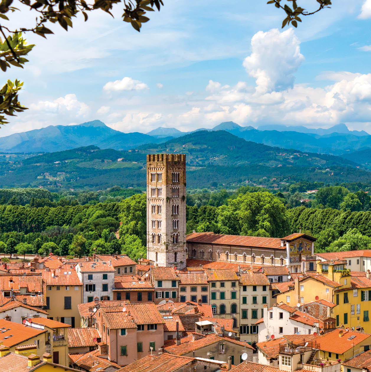 A view of the rooftops of the quaint Tuscan town of Lucca, Italy with mountain landscape in the background