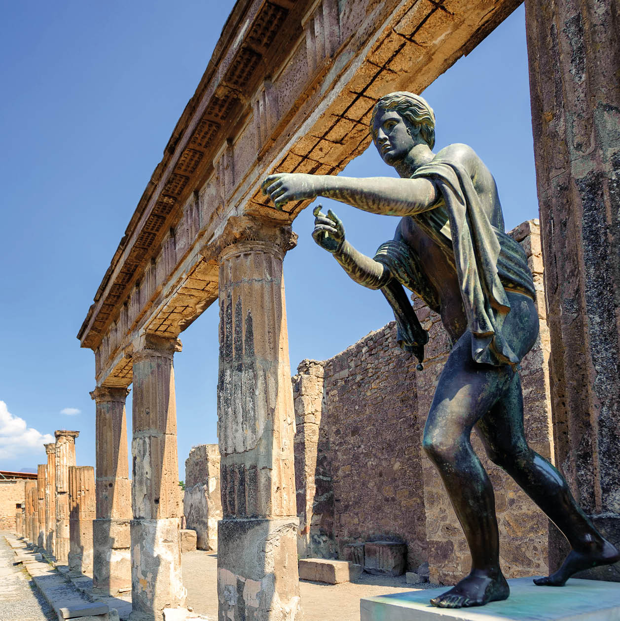 Ruins of the antique Temple of Apollo with bronze Apollo statue in Pompeii, Naples, Italy. Pompeii was destroyed by Vesuvius eruption in 79 AD.