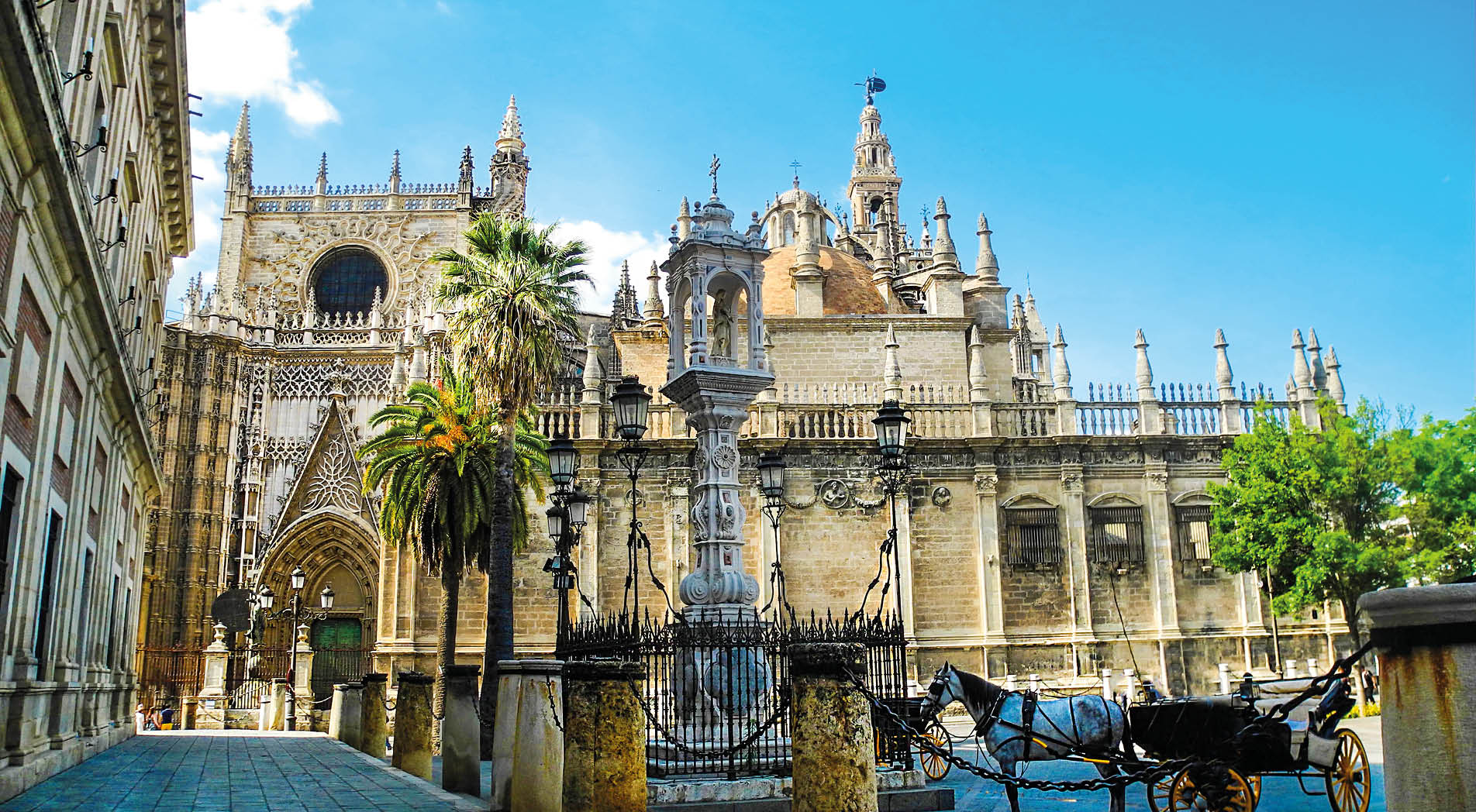 Sevilla cathedral and Giralda tower in Sevilla, Andalusia region, Spain. Horse carriage near the cathedral.