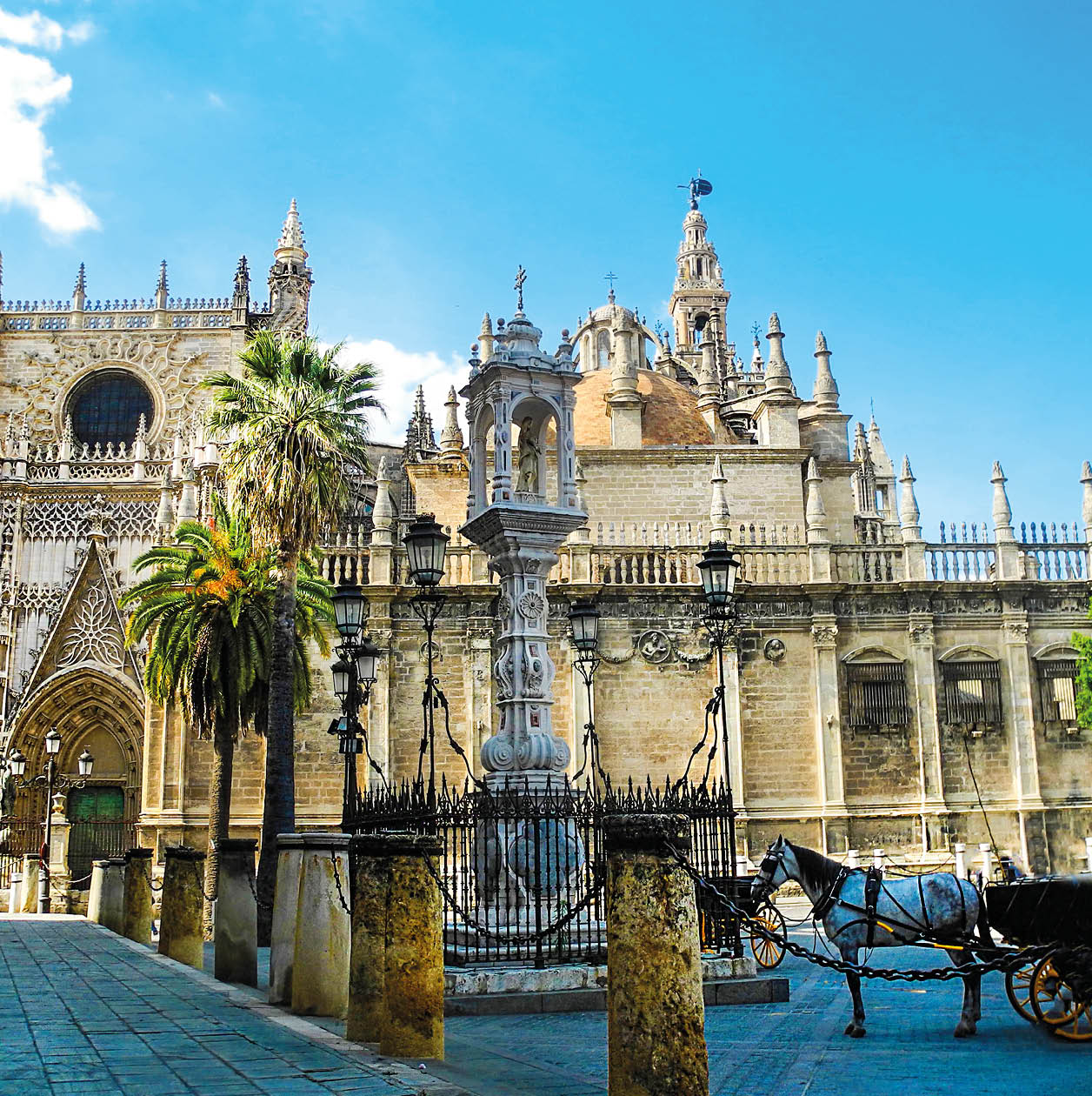 Sevilla cathedral and Giralda tower in Sevilla, Andalusia region, Spain. Horse carriage near the cathedral.