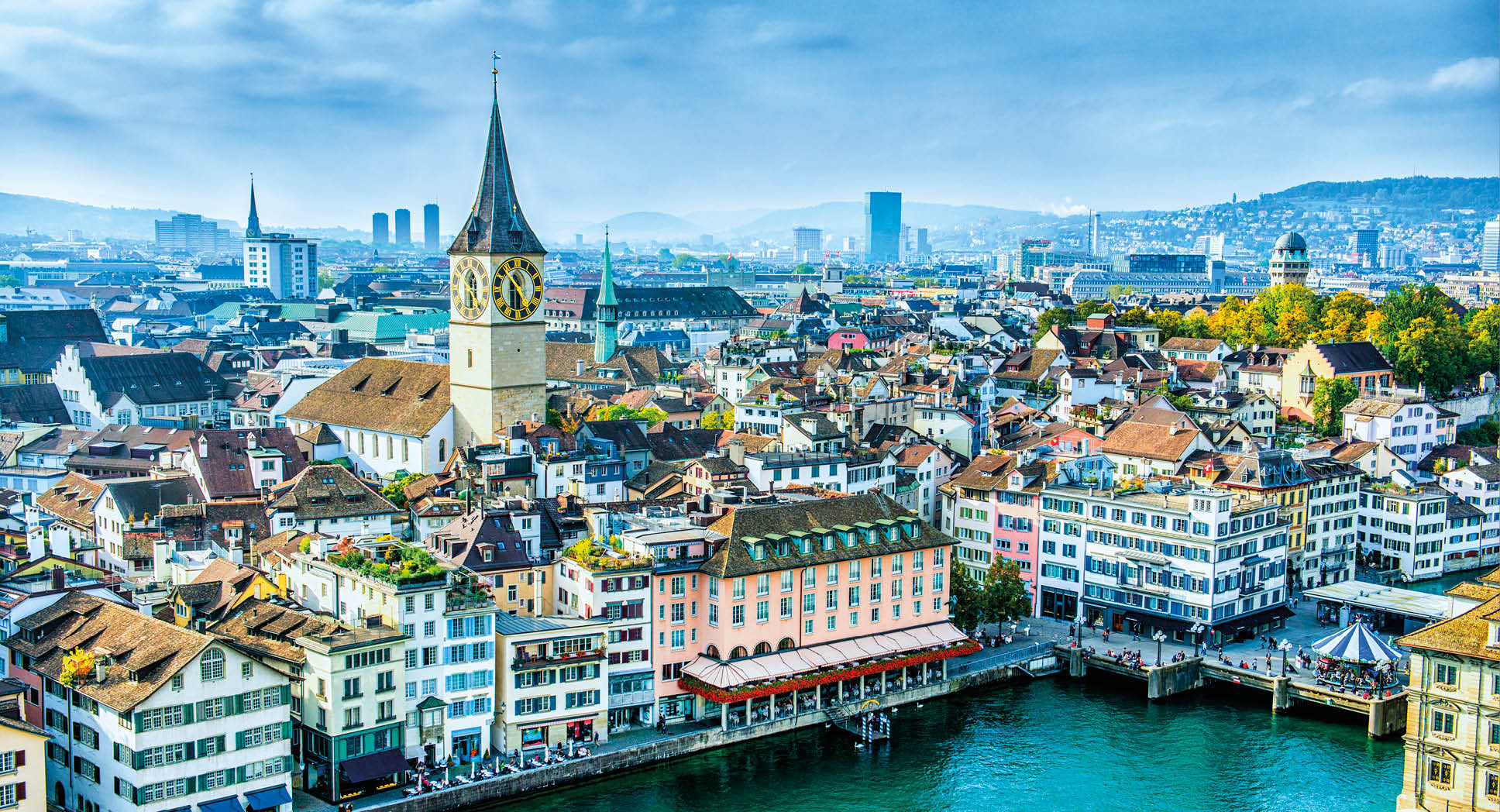 Aerial view of Zurich, Switzerland. Taken from a church tower overlooking the Limmat River. Beautiful blue sky with dramatic cloudscape over the city. Visible are many traditional Swiss houses, bridges and churches.