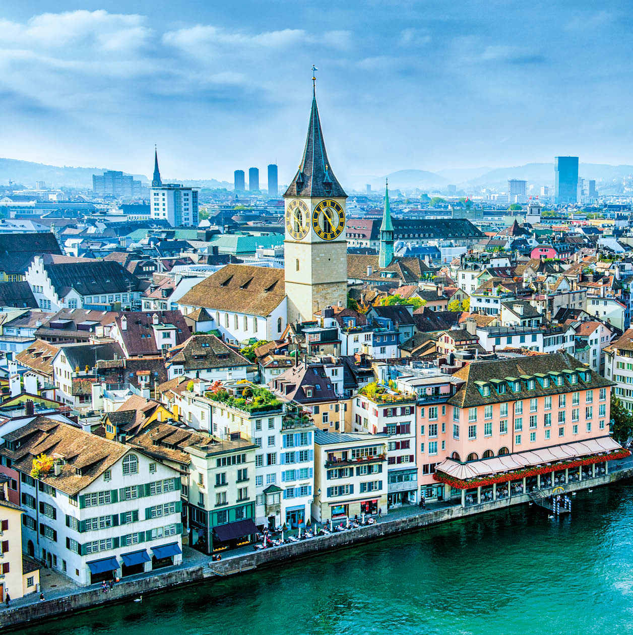 Aerial view of Zurich, Switzerland. Taken from a church tower overlooking the Limmat River. Beautiful blue sky with dramatic cloudscape over the city. Visible are many traditional Swiss houses, bridges and churches.