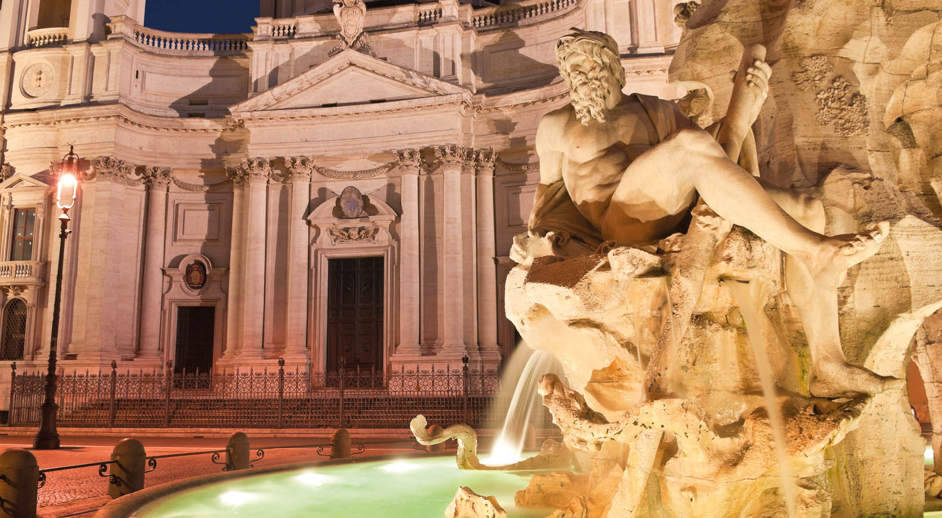 Fountain of the Four Rivers (1651) overlooked by the church of Sant'Agnese in Agone in the beautifully Baroque Piazza Navona (1651) illuminated by pretty streelights.