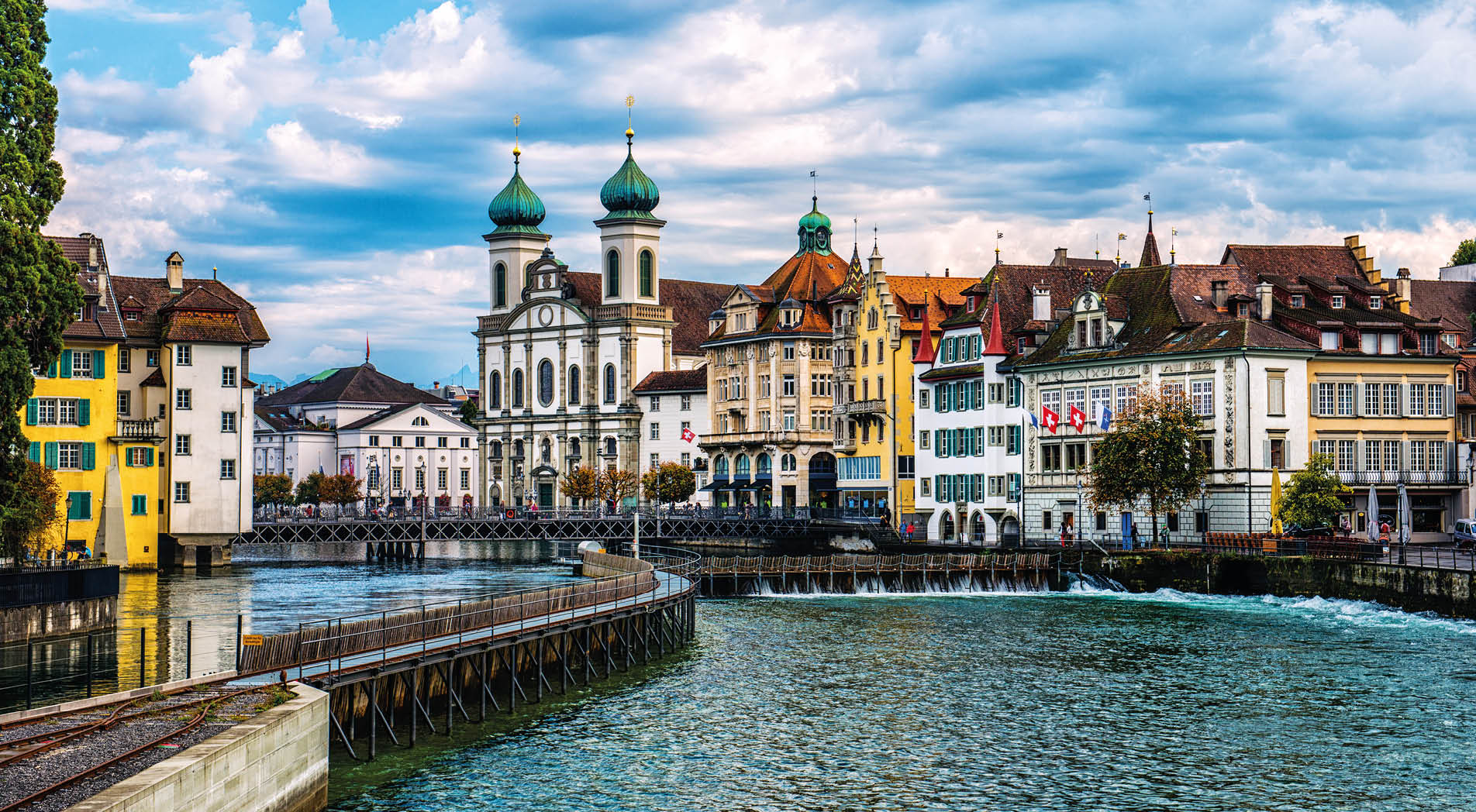 Beautiful Cityscape of old town Lucerne, visible are Jesuit Church, the river Reuss waterfront of Lucerne with the famous Kapellbrucke bridge built in 1333, traditional swiss buildings, restaurants, coffee bars, hotels, beautiful cloudscape and reflection in the water. 