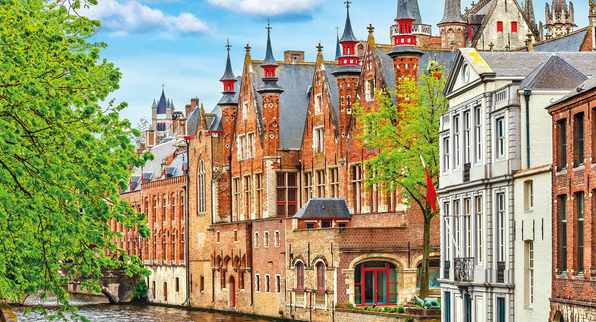 Medieval town Bruges in Belgium. Panorama and landscape vintage channel with old brick house broach on roof. Spring sunny day blue sky white cloud end green trees.