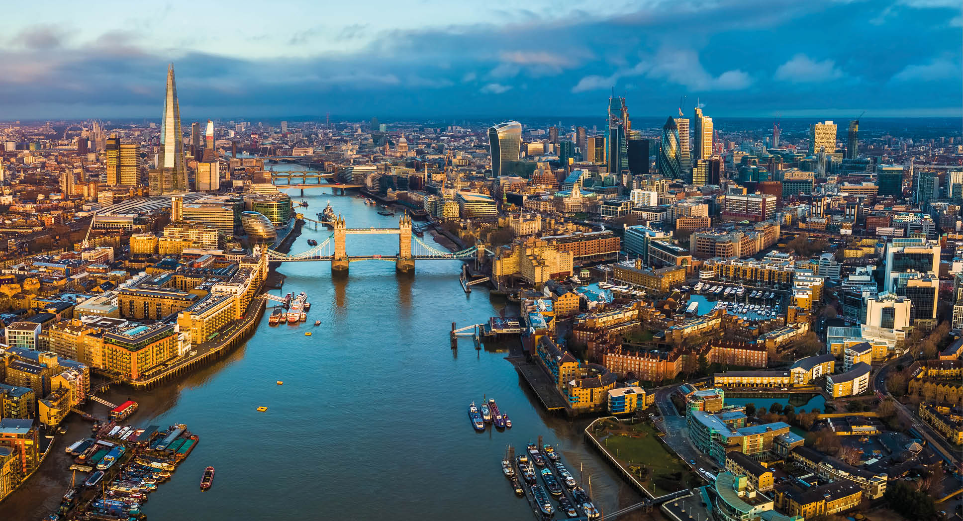 London, England - Panoramic aerial skyline view of London including Tower Bridge with red double-decker bus, Tower of London, skyscrapers of Bank District and other famous skyscrapers at golden hour