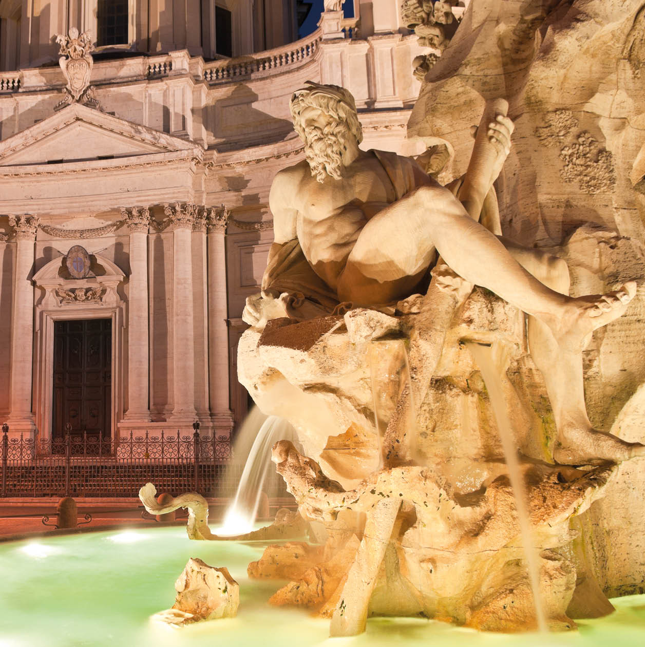 Fountain of the Four Rivers (1651) overlooked by the church of Sant'Agnese in Agone in the beautifully Baroque Piazza Navona (1651) illuminated by pretty streelights.