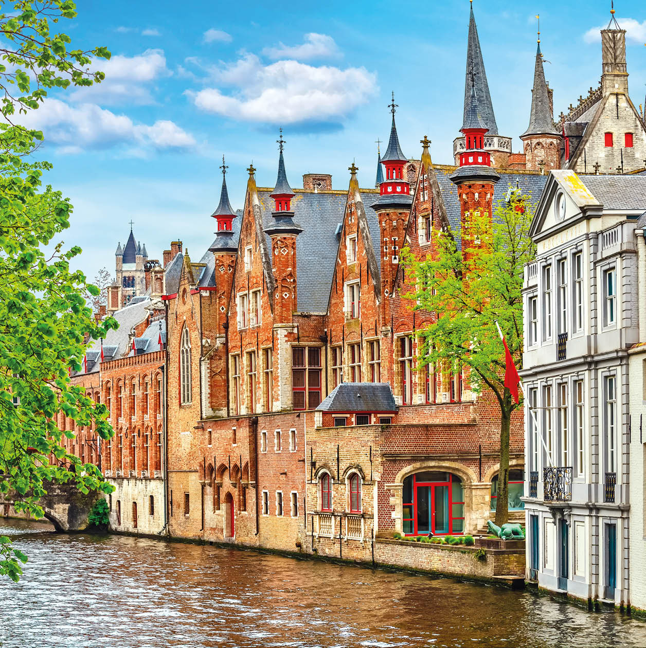 Medieval town Bruges in Belgium. Panorama and landscape vintage channel with old brick house broach on roof. Spring sunny day blue sky white cloud end green trees.