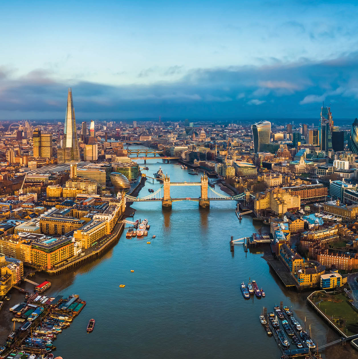 London, England - Panoramic aerial skyline view of London including Tower Bridge with red double-decker bus, Tower of London, skyscrapers of Bank District and other famous skyscrapers at golden hour