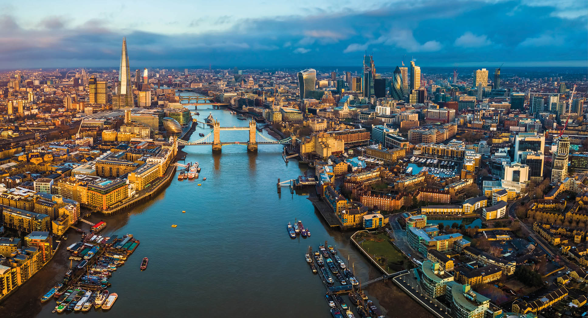 London, England - Panoramic aerial skyline view of London including Tower Bridge with red double-decker bus, Tower of London, skyscrapers of Bank District and other famous skyscrapers at golden hour