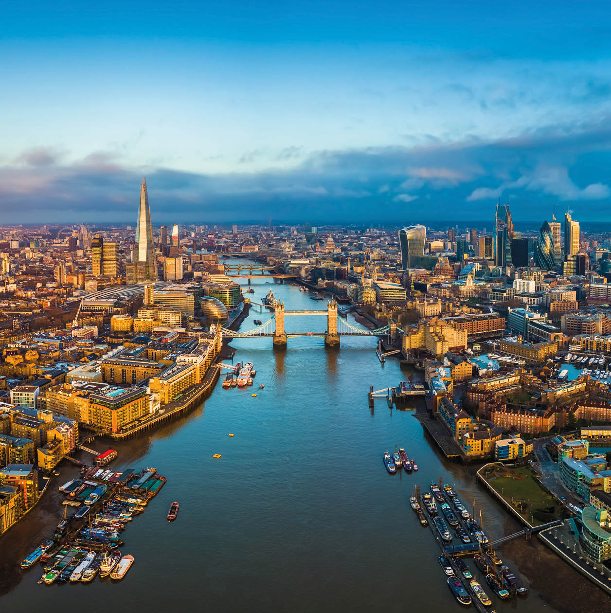 London, England - Panoramic aerial skyline view of London including Tower Bridge with red double-decker bus, Tower of London, skyscrapers of Bank District and other famous skyscrapers at golden hour