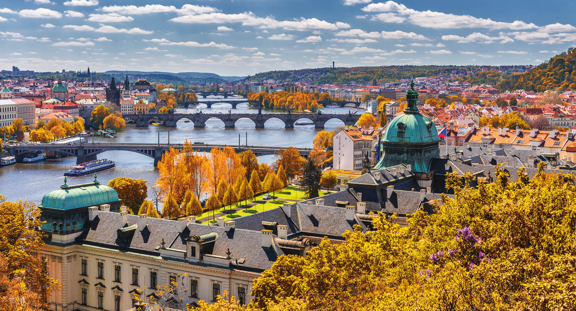 View to the historical bridges, Prague old town and Vltava river from popular view point in the Letna park (Letenske sady), beautiful autumn landscape in soft yellow light, Czech Republic