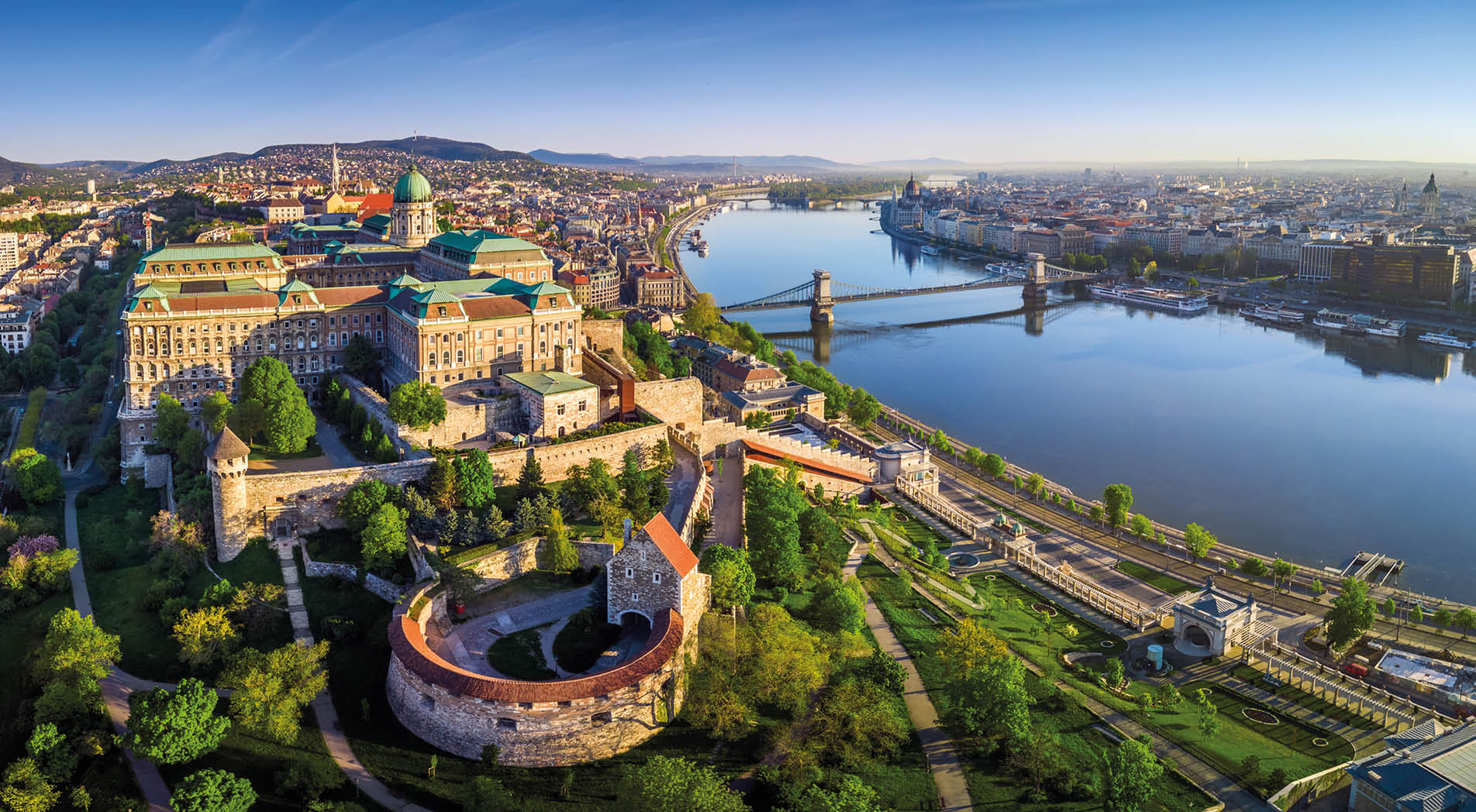 Budapest, Hungary - Aerial panoramic skyline view of Buda Castle Royal Palace with Szechenyi Chain Bridge, St.Stephen's Basilica, Hungarian Parliament and Matthias Church at sunrise with blue sky