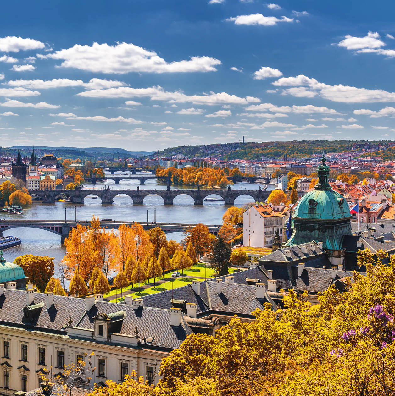View to the historical bridges, Prague old town and Vltava river from popular view point in the Letna park (Letenske sady), beautiful autumn landscape in soft yellow light, Czech Republic
