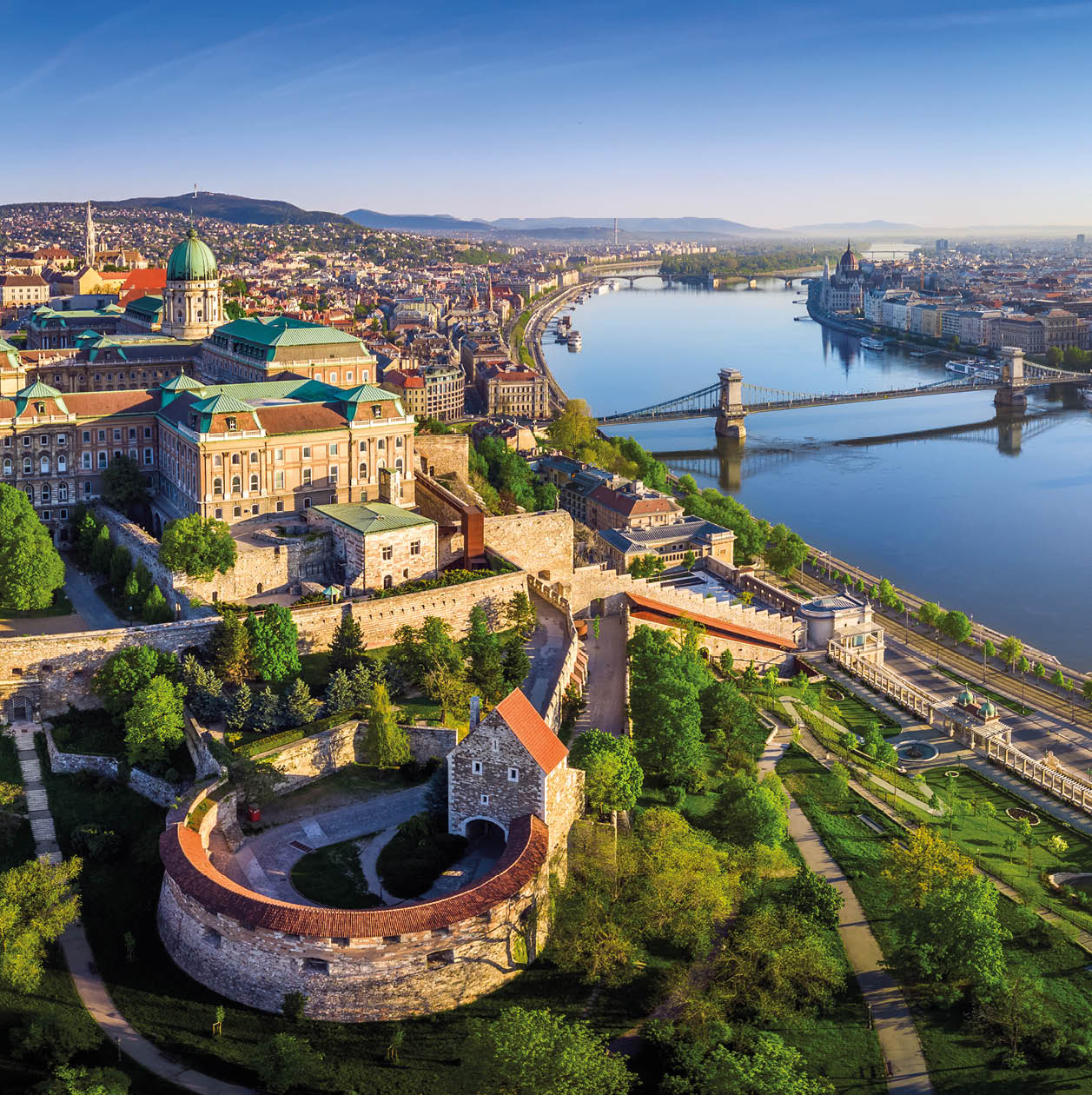 Budapest, Hungary - Aerial panoramic skyline view of Buda Castle Royal Palace with Szechenyi Chain Bridge, St.Stephen's Basilica, Hungarian Parliament and Matthias Church at sunrise with blue sky