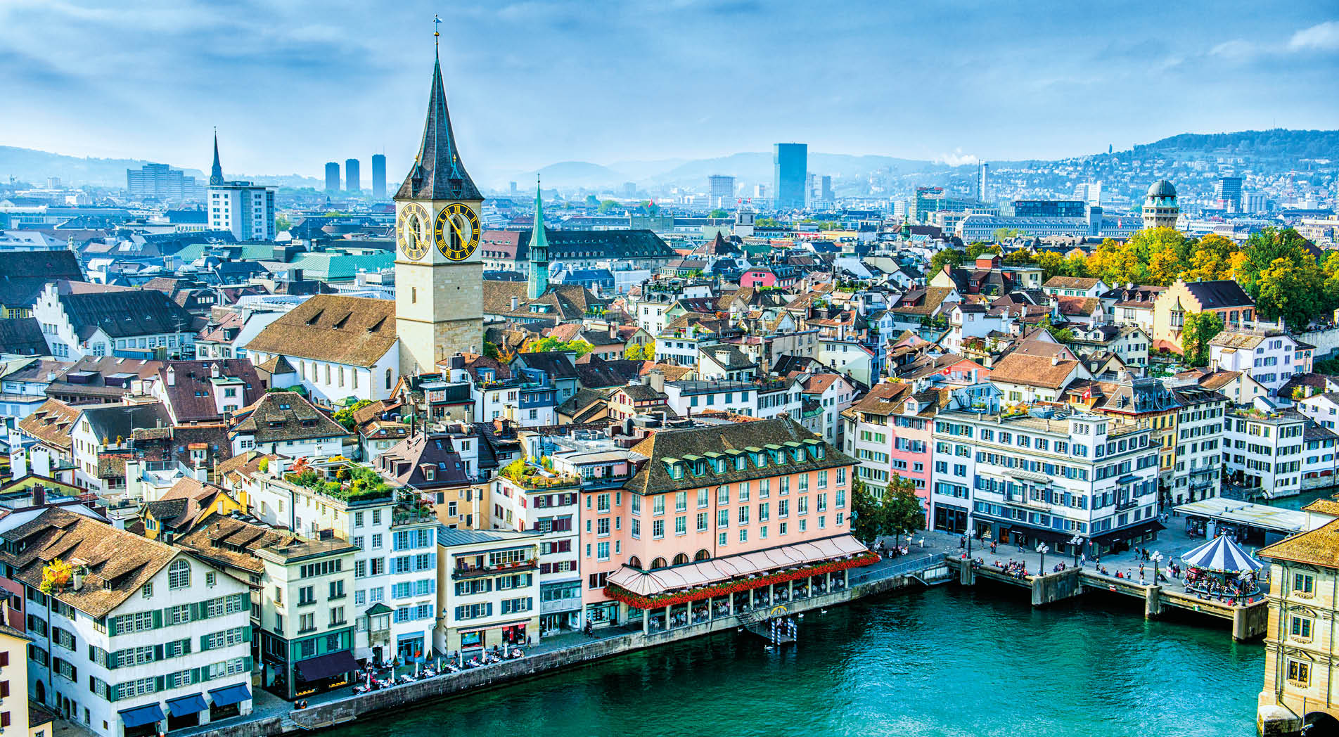 Aerial view of Zurich, Switzerland. Taken from a church tower overlooking the Limmat River. Beautiful blue sky with dramatic cloudscape over the city. Visible are many traditional Swiss houses, bridges and churches.