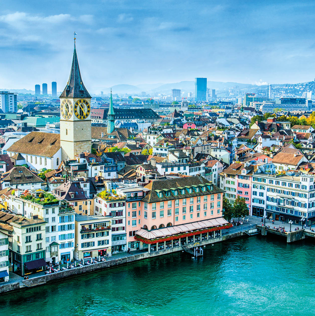 Aerial view of Zurich, Switzerland. Taken from a church tower overlooking the Limmat River. Beautiful blue sky with dramatic cloudscape over the city. Visible are many traditional Swiss houses, bridges and churches.