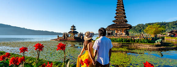Young couple tourist relaxing and enjoying the beautiful view at Ulun Danu Beratan temple in Bali, Indonesia
