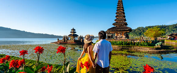 Young couple tourist relaxing and enjoying the beautiful view at Ulun Danu Beratan temple in Bali, Indonesia